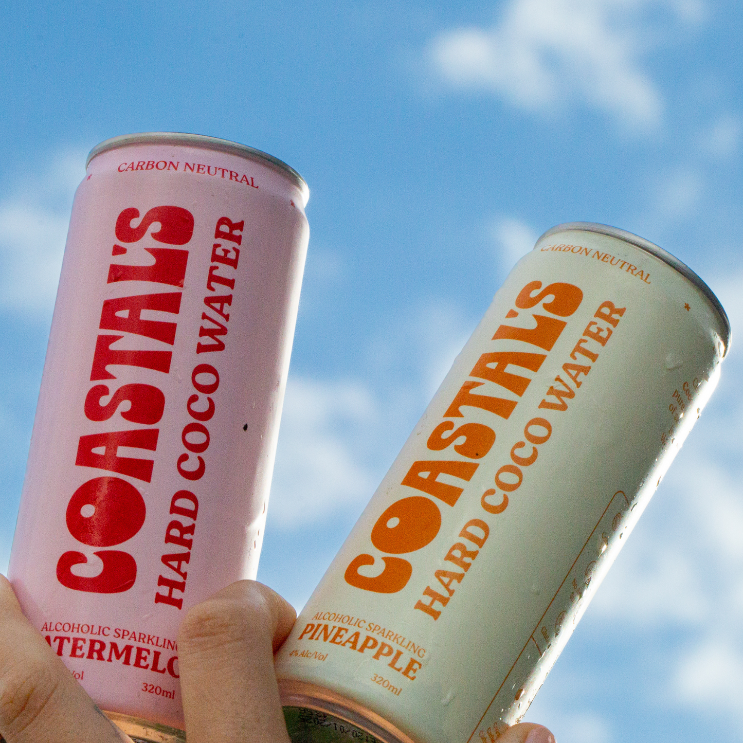 Two cans of Coastals Hard Coco Water against a blue sky background